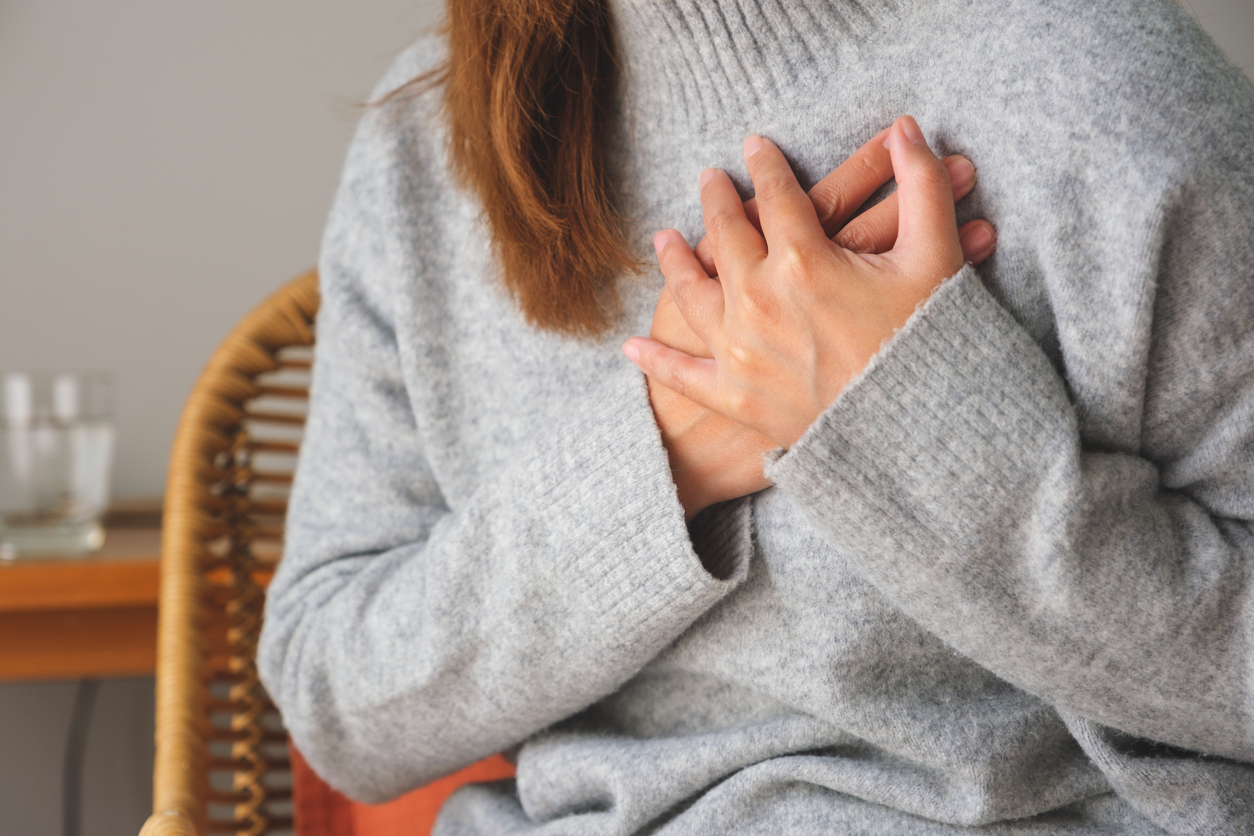 Closeup image of a woman with hands on chest, sudden heart attack, suffering from chest pain